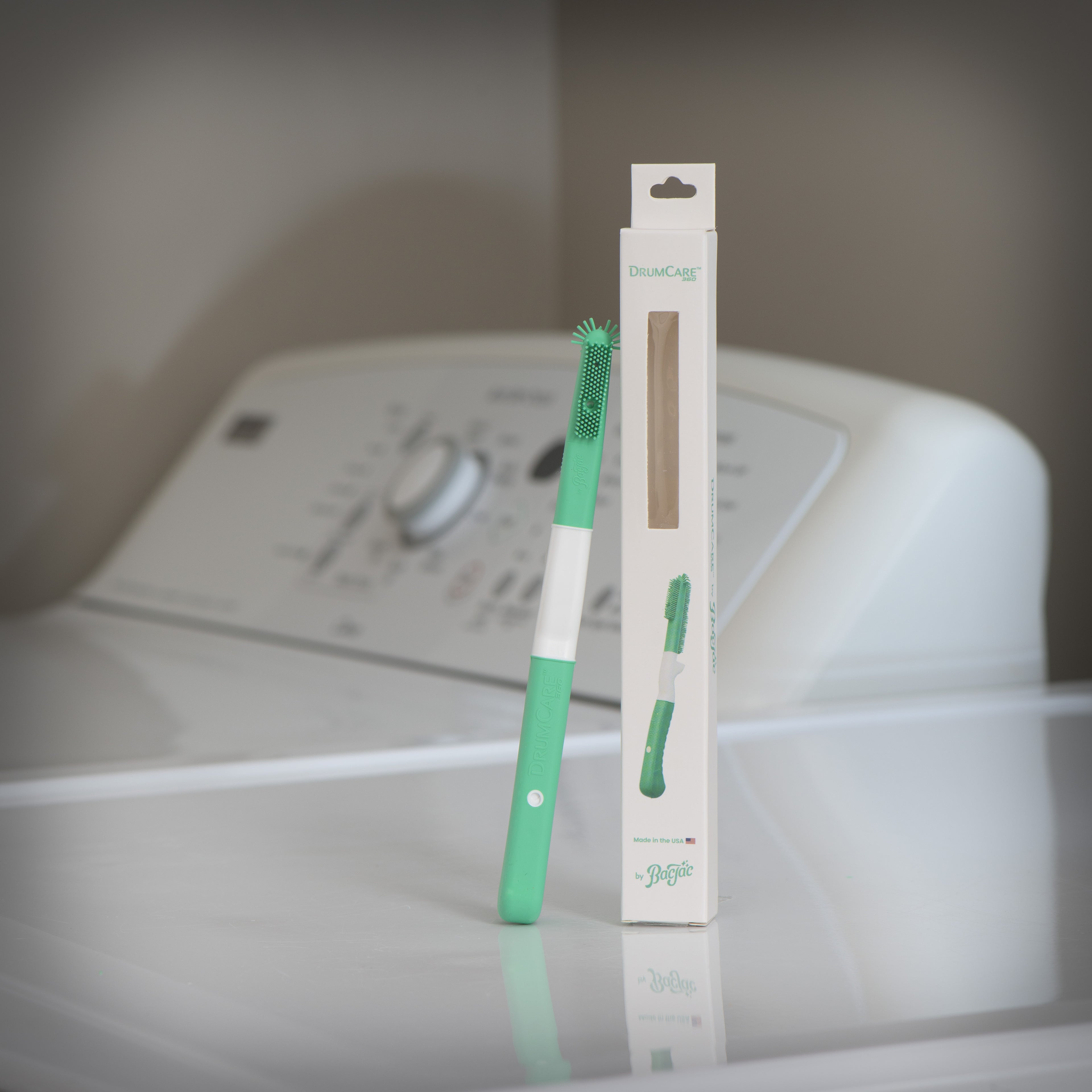 Green silicone cleaning brush with packaging on a washing machine